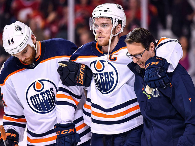 CALGARY, AB - APRIL 06: Edmonton Oilers Center Connor McDavid (97) is helped off the ice by Edmonton Oilers Right Wing Zack Kassian (44) and a trainer after crashing into Calgary Flames net during the second period of an NHL game where the Calgary Flames hosted the Edmonton Oilers on April 6, 2019, at the Scotiabank Saddledome in Calgary, AB.