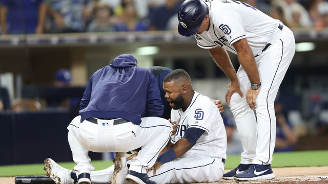 SAN DIEGO, CALIFORNIA - AUGUST 27: Manager Andy Green and third base coach Glenn Hoffman tend to Manuel Margot #7 of the San Diego Padres after he was hit by a pitch during the second inning of a game against the Los Angeles Dodgersat PETCO Park on August 27, 2019 in San Diego, California.