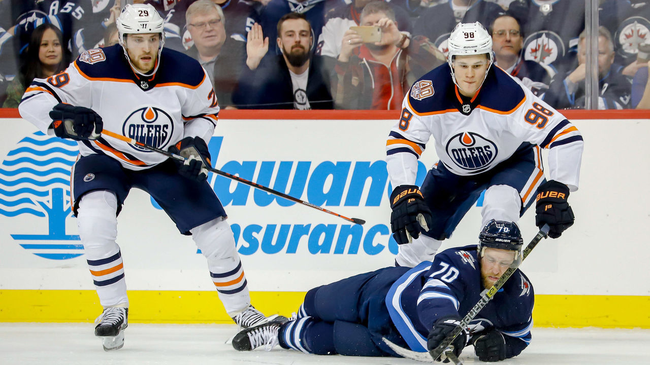 WINNIPEG, MB - OCTOBER 16: Joe Morrow #70 of the Winnipeg Jets plays the puck away from Leon Draisaitl #29 and Jesse Puljujarvi #98 of the Edmonton Oilers during third period action at the Bell MTS Place on October 16, 2018 in Winnipeg, Manitoba, Canada.