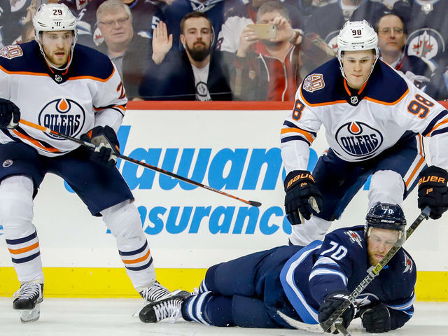 WINNIPEG, MB - OCTOBER 16: Joe Morrow #70 of the Winnipeg Jets plays the puck away from Leon Draisaitl #29 and Jesse Puljujarvi #98 of the Edmonton Oilers during third period action at the Bell MTS Place on October 16, 2018 in Winnipeg, Manitoba, Canada.