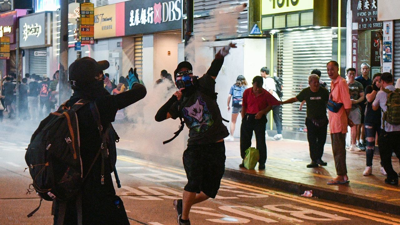 TOPSHOT - A protester returns a tear gas canister fired by riot police in Causeway Bay in Hong Kong on September 8, 2019. - Riot police on September 8 chased groups of hardcore protesters who blocked roads, vandalised nearby subway stations and set makeshift barricades on fire as the evening set in, while an earlier main daytime rally saw pro-democracy activists marching to the United States consulate in Hong Kong in a bid to ramp up international pressure on Beijing following three months of huge and sometimes violent protests.