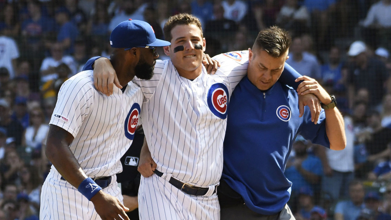 CHICAGO, ILLINOIS - SEPTEMBER 15: Anthony Rizzo of the Chicago Cubs is helped off the field by Jason Heyward (L) and trainer PJ Mainville after being injured against the Pittsburgh Pirates during the third inning at Wrigley Field on September 15, 2019 in Chicago, Illinois.