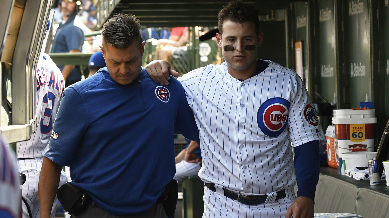 CHICAGO, ILLINOIS - SEPTEMBER 15: Anthony Rizzo #44 of the Chicago Cubs is helped in the dugout by trainer PJ Mainville after being injured against the Pittsburgh Pirates during the third inning at Wrigley Field on September 15, 2019 in Chicago, Illinois.