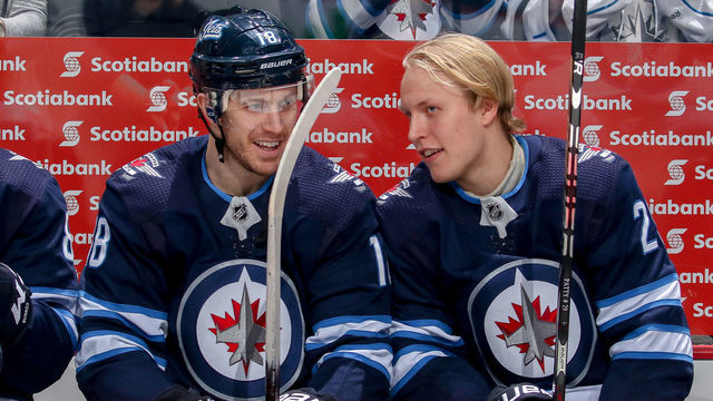 WINNIPEG, MB - DECEMBER 16: Bryan Little #18 and Patrik Laine #29 of the Winnipeg Jets share a laugh at the bench prior to puck drop against the Tampa Bay Lightning at the Bell MTS Place on December 16, 2018 in Winnipeg, Manitoba, Canada.