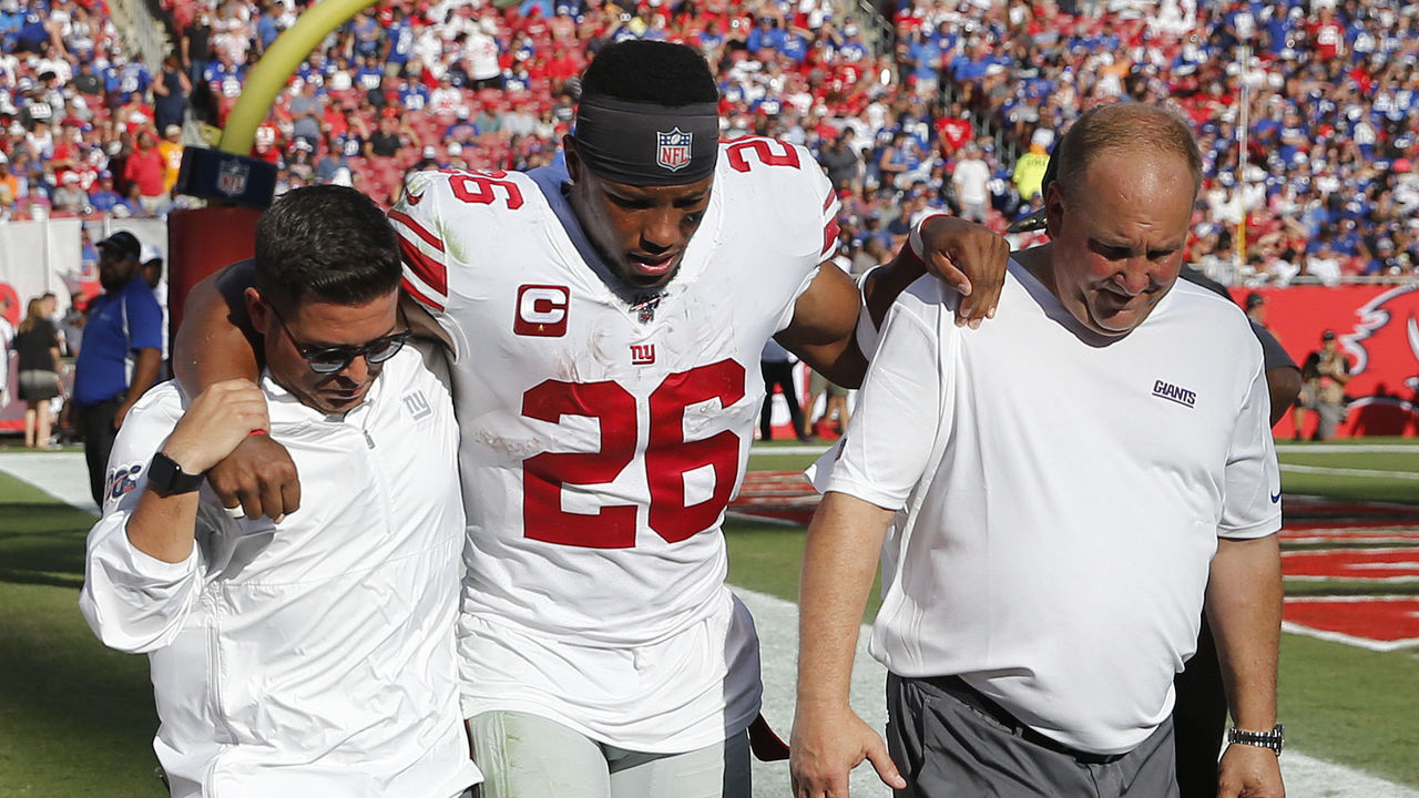 TAMPA, FLORIDA - SEPTEMBER 22: Running back Saquon Barkley #26 of the New York Giants is helped back to the locker room by medical staff after an injury during the game against the Tampa Bay Buccaneers at Raymond James Stadium on September 22, 2019 in Tampa, Florida.