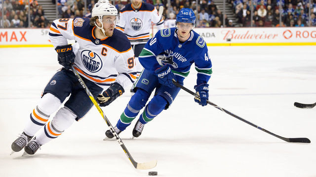 VANCOUVER, BC - DECEMBER 16: Edmonton Oilers Center Connor McDavid (97) carries the puck ahead of Vancouver Canucks Center Elias Pettersson (40) during their NHL game at Rogers Arena on December 16, 2018 in Vancouver, British Columbia, Canada.