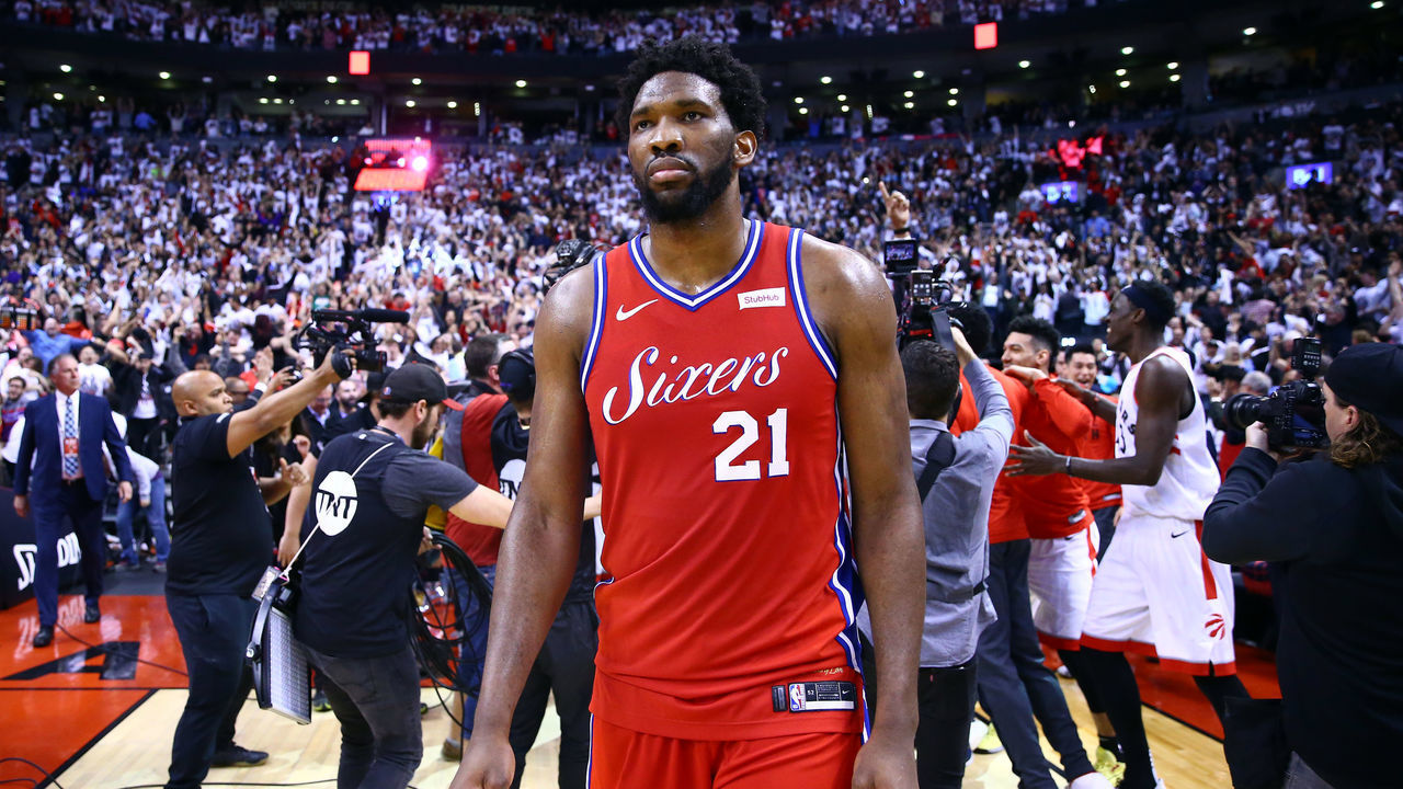 TORONTO, ON - MAY 12: Joel Embiid #21 of the Philadelphia 76ers looks on as Kawhi Leonard #2 of the Toronto Raptors celebrates with teammates after sinking a buzzer beater to win Game Seven of the second round of the 2019 NBA Playoffs at Scotiabank Arena on May 12, 2019 in Toronto, Canada.