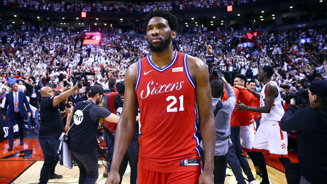 TORONTO, ON - MAY 12: Joel Embiid #21 of the Philadelphia 76ers looks on as Kawhi Leonard #2 of the Toronto Raptors celebrates with teammates after sinking a buzzer beater to win Game Seven of the second round of the 2019 NBA Playoffs at Scotiabank Arena on May 12, 2019 in Toronto, Canada.