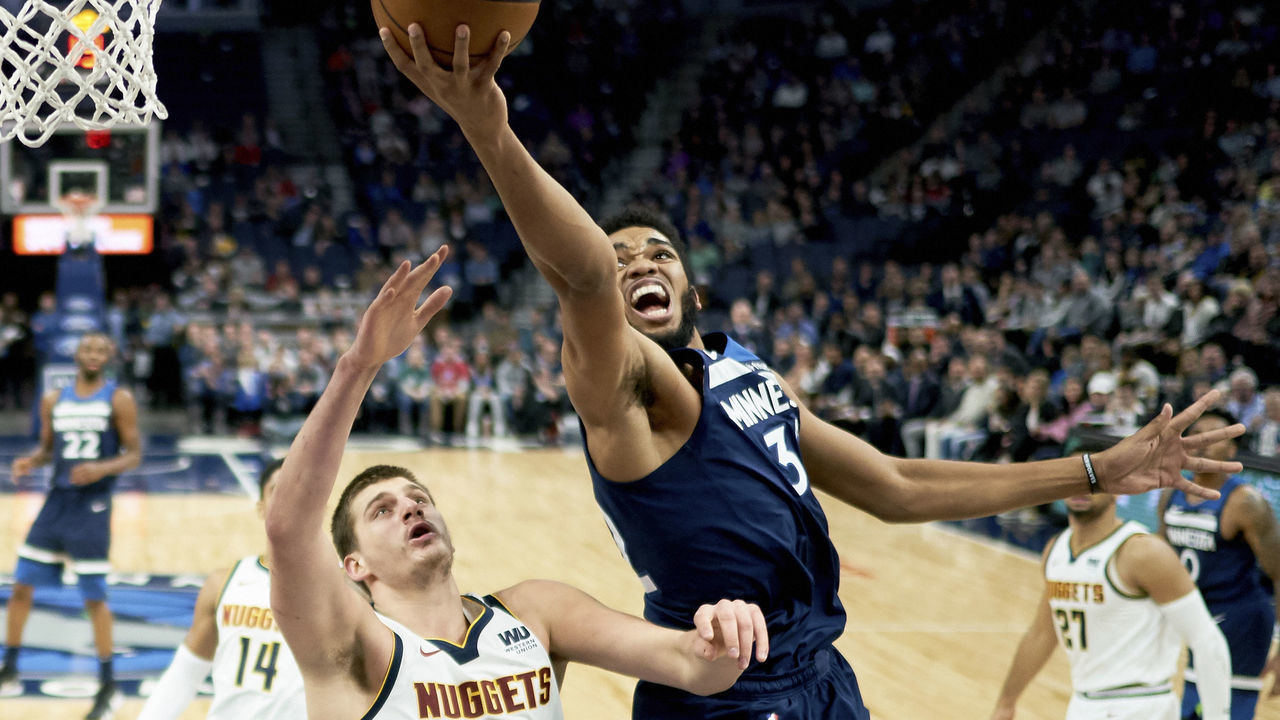 MINNEAPOLIS, MN - NOVEMBER 21: Karl-Anthony Towns #32 of the Minnesota Timberwolves shoots the ball against Nikola Jokic #15 of the Denver Nuggets during the game on November 21, 2018 at the Target Center in Minneapolis, Minnesota.