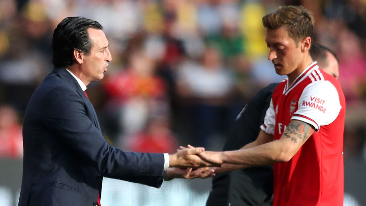 Arsenal manager Unai Emery greets team-mate Mesut Ozil as he is substituted off during the Premier League match at Vicarage Road, Watford.