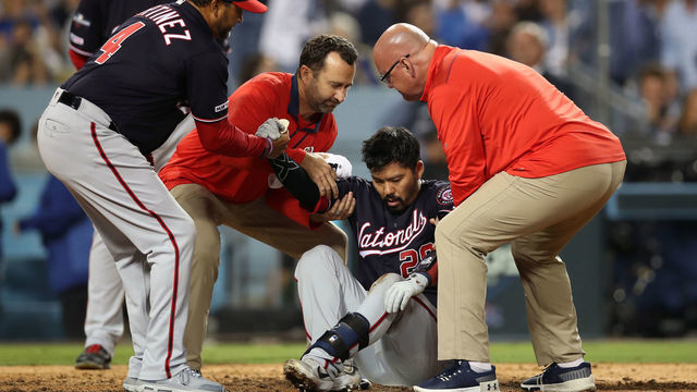 LOS ANGELES, CA - OCTOBER 09: Kurt Suzuki #28 of the Washington Nationals is helped to his feet after being hit by a pitch in the top of the seventh inning during Game 5 of the NLDS between the Washington Nationals and the Los Angeles Dodgers at Dodger Stadium on Wednesday, October 9, 2019 in Los Angeles, California.