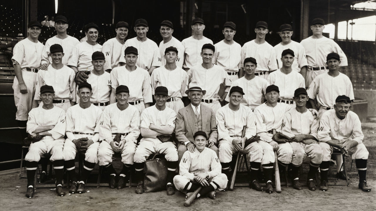 (Original Caption) This is the gang that will face the Giants in the World Series which starts off next week. Front row, left to right; Sam Rice, Walter Stewart, Leon Goslin, Al Schacht, President Clark Griffith, Manager Joe Cronin, Dave Harris, Cliff Bolton and Nick Altrock, Second Row left to right: Jack Russell, Al Thomas, Ed Chapman, Cecil Travis, Rog Burke, John Kerr, Monte Weaver and Buddy Myer. Third row, left to right: Luke Sewell, Moe Berg, Earl Whitehill- Ray Prim.- Fred Schulte Heinie Mansb, Alex McColl-0ssie Bluage- Jow Kuhel, Alvin Crowder and Bob Boken. Seated in front of Griffith is the mascot Mahorney. The World Series starts Oct. 3rd.