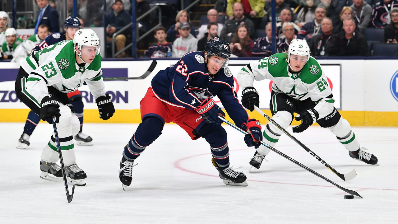 COLUMBUS, OH - OCTOBER 16: Sonny Milano #22 of the Columbus Blue Jackets skates the puck between Esa Lindell #23 and Roope Hintz #24 of the Dallas Stars during the third period of a game on October 16, 2019 at Nationwide Arena in Columbus, Ohio.
