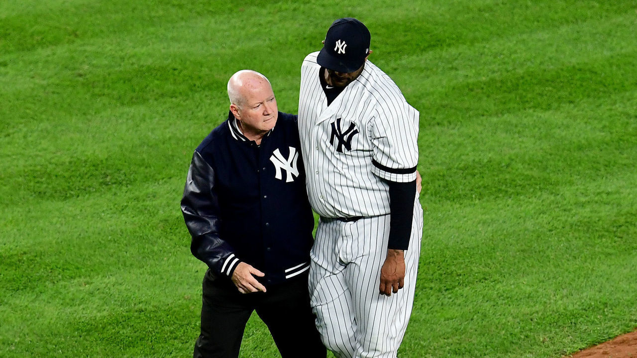 NEW YORK, NEW YORK - OCTOBER 17: Head athletic trainer Steve Donohue walks CC Sabathia #52 of the New York Yankees off the field during the eighth inning of game four of the American League Championship Series against the Houston Astros at Yankee Stadium on October 17, 2019 in the Bronx borough of New York City.
