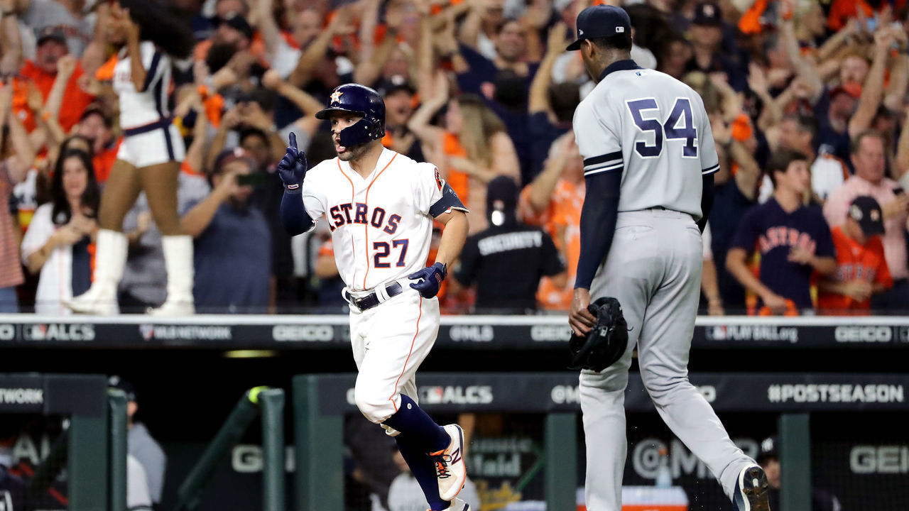 HOUSTON, TEXAS - OCTOBER 19: Jose Altuve #27 of the Houston Astros comes home to score following his ninth inning walk-off two-run home run as Aroldis Chapman #54 of the New York Yankees walks off the field in game six of the American League Championship Series at Minute Maid Park on October 19, 2019 in Houston, Texas. The Astros defeated the Yankees 6-4.