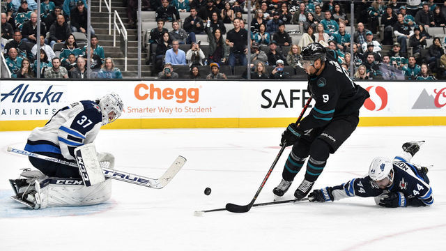SAN JOSE, CA - NOVEMBER 1: Evander Kane #9 of the San Jose Sharks crashes the net against Connor Hellebuyck #37 of the Winnipeg Jets at SAP Center on November 1, 2019 in San Jose, California.