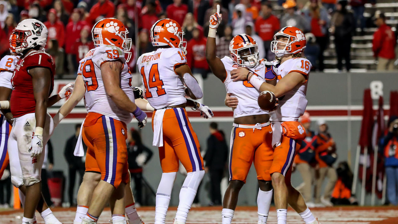 RALEIGH, NC - NOVEMBER 09: Clemson Tigers quarterback Trevor Lawrence (16), Clemson Tigers wide receiver Diondre Overton (14) and Clemson Tigers offensive lineman Gage Cervenka (59) celebrate a touchdown with Clemson Tigers running back Travis Etienne (9) during an NCAA Football Game between the North Carolina State Wolfpack and the Clemson Tigers on November 9, 2019 at Carter-Finley Stadium in Raleigh, NC.