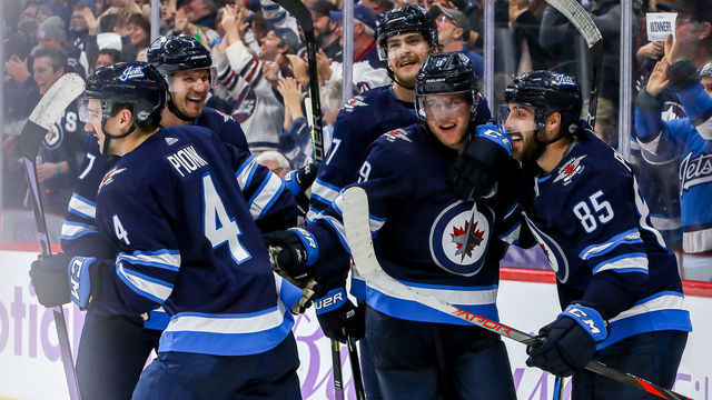 WINNIPEG, MB - NOVEMBER 23: Dmitry Kulikov #7, Neal Pionk #4, Adam Lowry #17, Andrew Copp #9 and Mathieu Perreault #85 of the Winnipeg Jets celebrate a third period goal against the Columbus Blue Jackets at the Bell MTS Place on November 23, 2019 in Winnipeg, Manitoba, Canada.