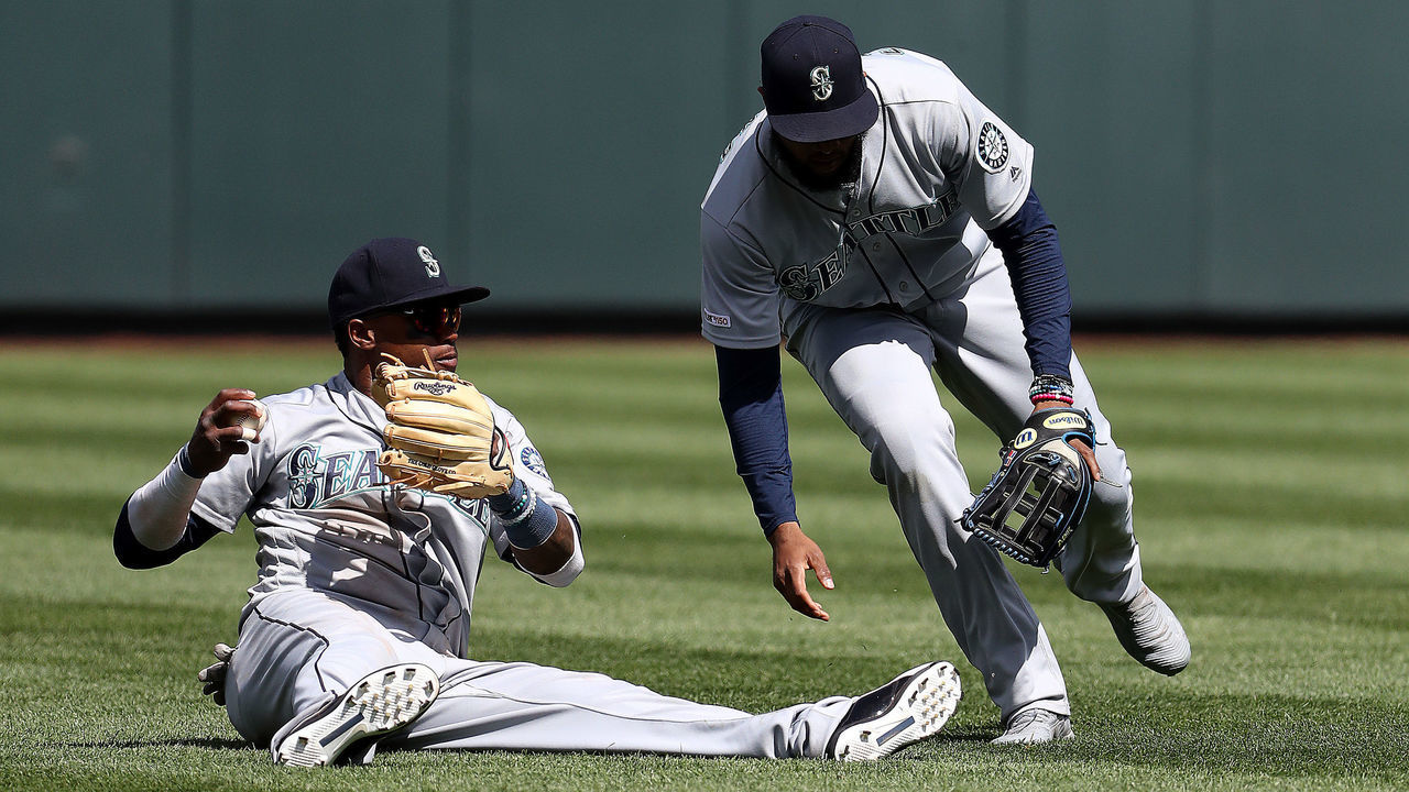 KANSAS CITY, MISSOURI - APRIL 11: Tim Beckham #1 of the Seattle Mariners mishandles the ball off the bat of Alex Gordon #4 of the Kansas City Royals while Domingo Santana #16 looks on during the 7th inning of the game at Kauffman Stadium on April 11, 2019 in Kansas City, Missouri.