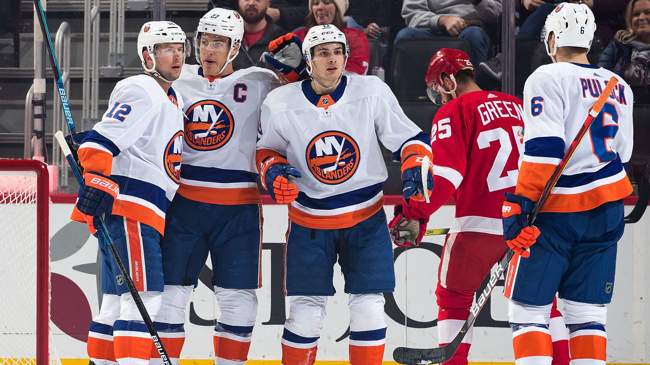 DETROIT, MI - DECEMBER 02: Anders Lee #27 of the New York Islanders celebrates his first period goal with teammates Josh Bailey #12, Mathew Barzal #13 and Ryan Pulock #6 as Mike Green #25 of the Detroit Red Wings skates past during an NHL game at Little Caesars Arena on December 2, 2019 in Detroit, Michigan.