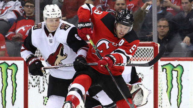 NEWARK, NEW JERSEY - OCTOBER 25: The puck gets past Jakob Chychrun #6 of the Arizona Coyotes and Taylor Hall #9 of the New Jersey Devils and is topped by Antti Raanta #32 during the second period at the Prudential Center on October 25, 2019 in Newark, New Jersey.