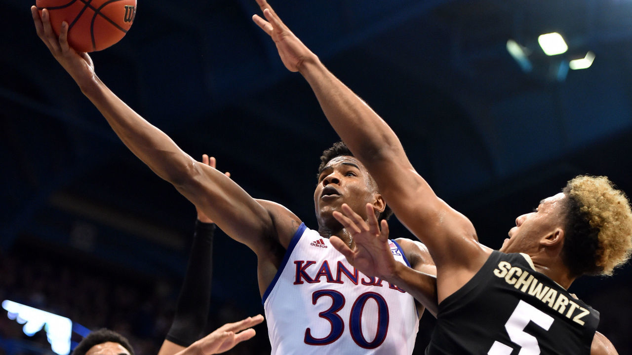 LAWRENCE, KANSAS - DECEMBER 07: Ochai Agbaji #30 of the Kansas Jayhawks lays the ball up against Tyler Bey #1 and D'Shawn Schwartz #5 of the Colorado Buffaloes in the first half at Allen Fieldhouse on December 07, 2019 in Lawrence, Kansas.