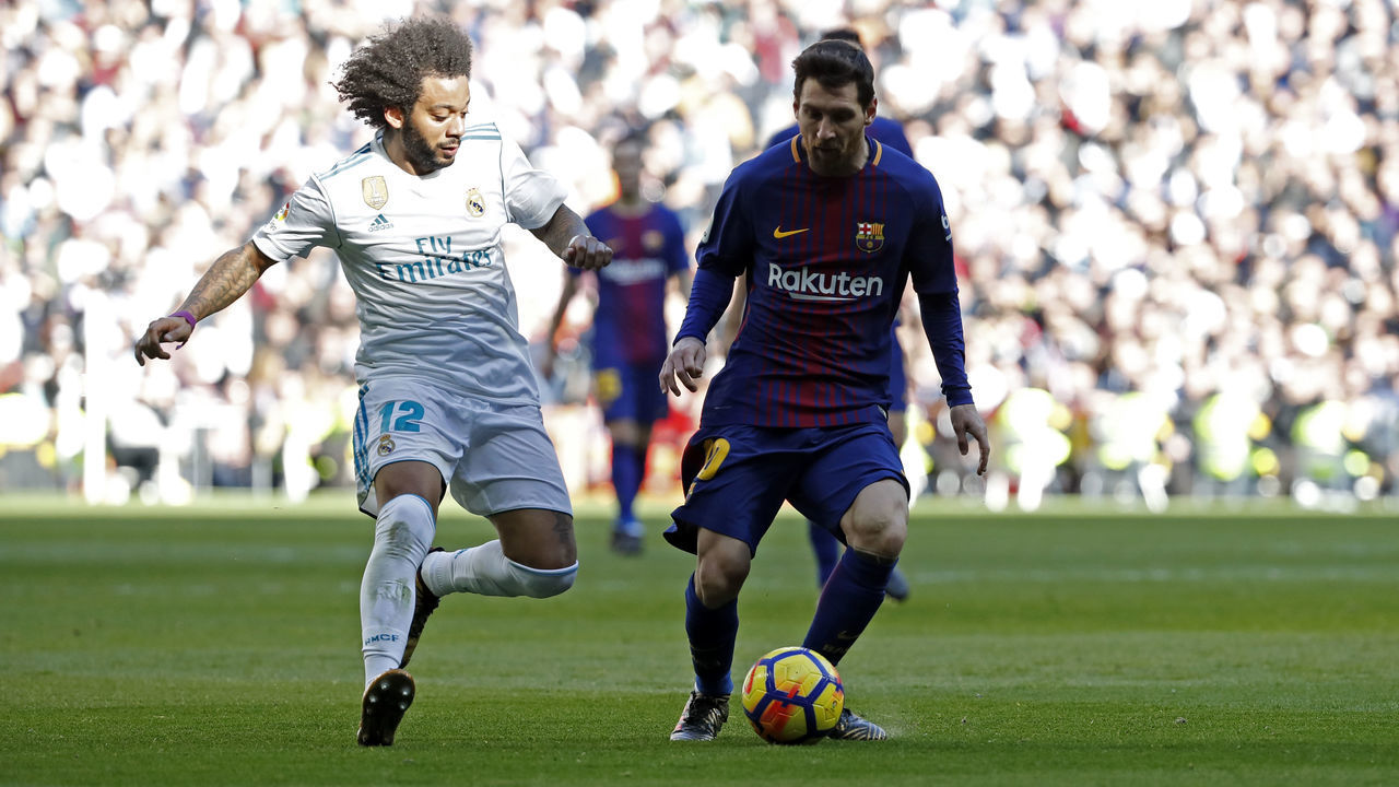 MADRID, SPAIN - DECEMBER 23: Marcelo of Real Madrid and Lionel Messi of Barcelona battle for the ball during the La Liga match between Real Madrid and Barcelona at Estadio Santiago Bernabeu on December 23, 2017 in Madrid, Spain.