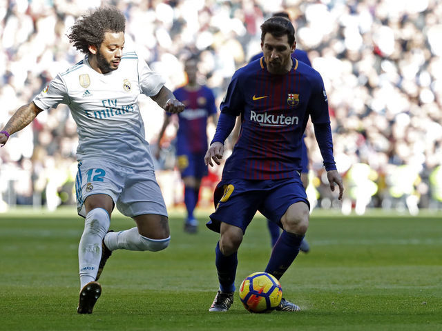 MADRID, SPAIN - DECEMBER 23: Marcelo of Real Madrid and Lionel Messi of Barcelona battle for the ball during the La Liga match between Real Madrid and Barcelona at Estadio Santiago Bernabeu on December 23, 2017 in Madrid, Spain.