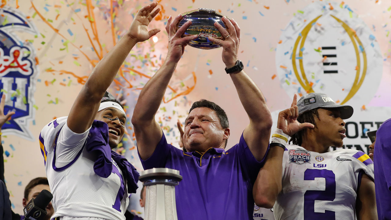 ATLANTA, GEORGIA - DECEMBER 28: Head coach Ed Orgeron of the LSU Tigers holds the Chick-fil-A Peach Bowl trophy on the podium with team after winning the Chick-fil-A Peach Bowl 28-63 over the Oklahoma Sooners at Mercedes-Benz Stadium on December 28, 2019 in Atlanta, Georgia.