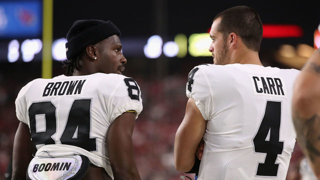 GLENDALE, ARIZONA - AUGUST 15: Wide receiver Antonio Brown #84 and quarterback Derek Carr #4 of the Oakland Raiders talk on the sidelines during the first half of the NFL preseason game against the Arizona Cardinals at State Farm Stadium on August 15, 2019 in Glendale, Arizona.