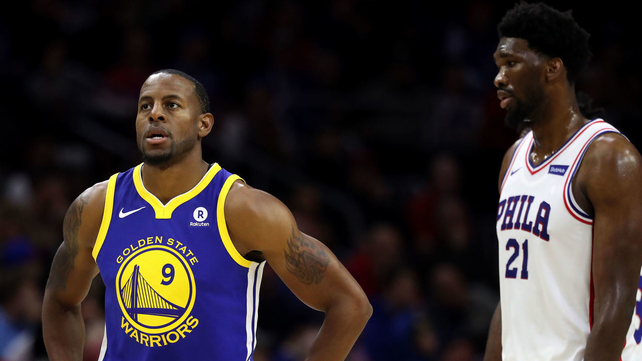 PHILADELPHIA, PA - NOVEMBER 18: Andre Iguodala #9 of the Golden State Warriors walks in front of Joel Embiid #21 of the Philadelphia 76ers at Wells Fargo Center on November 18, 2017 in Philadelphia,Pennsylvania.