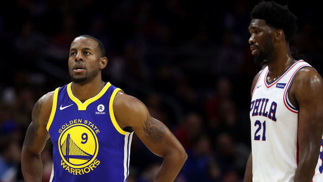 PHILADELPHIA, PA - NOVEMBER 18: Andre Iguodala #9 of the Golden State Warriors walks in front of Joel Embiid #21 of the Philadelphia 76ers at Wells Fargo Center on November 18, 2017 in Philadelphia,Pennsylvania.