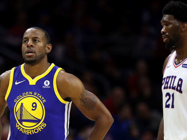 PHILADELPHIA, PA - NOVEMBER 18: Andre Iguodala #9 of the Golden State Warriors walks in front of Joel Embiid #21 of the Philadelphia 76ers at Wells Fargo Center on November 18, 2017 in Philadelphia,Pennsylvania.