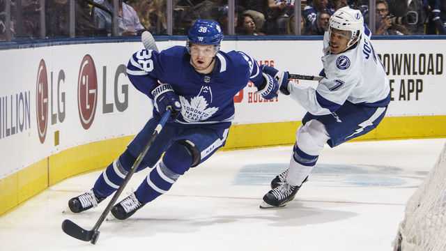 TORONTO, ON - OCTOBER 10: Rasmus Sandin #38 of the Toronto Maple Leafs plays the puck against Mathieu Joseph #7 of the Tampa Bay Lightning during the second period at the Scotiabank Arena on October 10, 2019 in Toronto, Ontario, Canada.