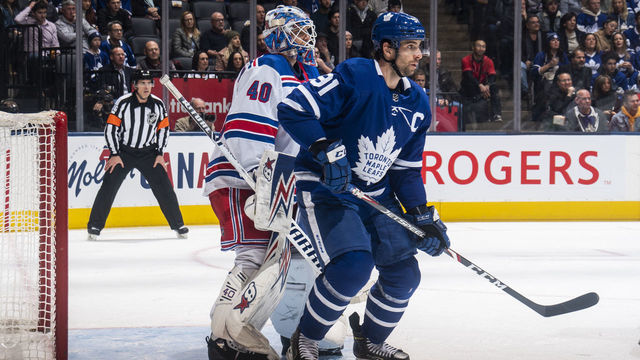 TORONTO, ON - DECEMBER 28: John Tavares #91 of the Toronto Maple Leafs battles in front of Alexandar Georgiev #40 of the New York Rangers during the second period at the Scotiabank Arena on December 28, 2019 in Toronto, Ontario, Canada.
