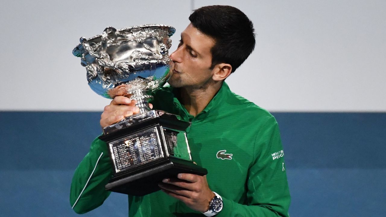 Serbia's Novak Djokovic kisses the Norman Brookes Challenge Cup trophy after beating Austria's Dominic Thiem in their men's singles final match on day fourteen of the Australian Open tennis tournament in Melbourne on February 3, 2020.