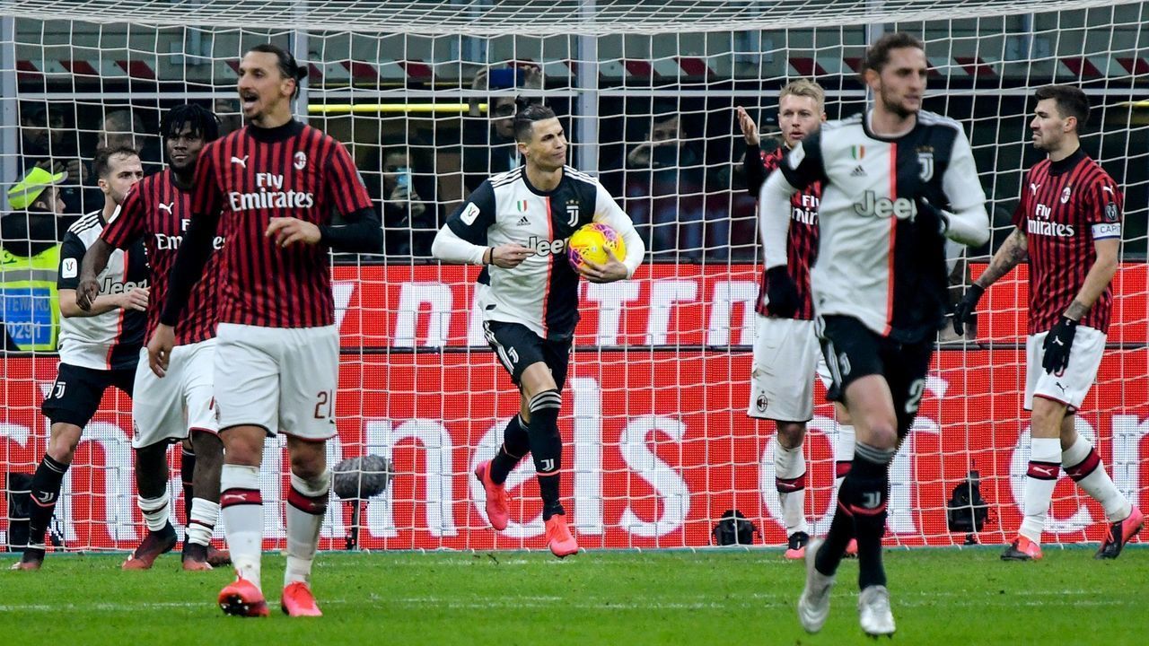 Juventus' Portuguese forward Cristiano Ronaldo (C) grabs the ball as he celebrates after scoring a penalty as AC Milan's Swedish forward Zlatan Ibrahimovic (L) reacts during the Italian Cup (Coppa Italia) semi-final first leg football match AC Milan vs Juventus Turin on February 13, 2020 at the San Siro stadium in Milan.