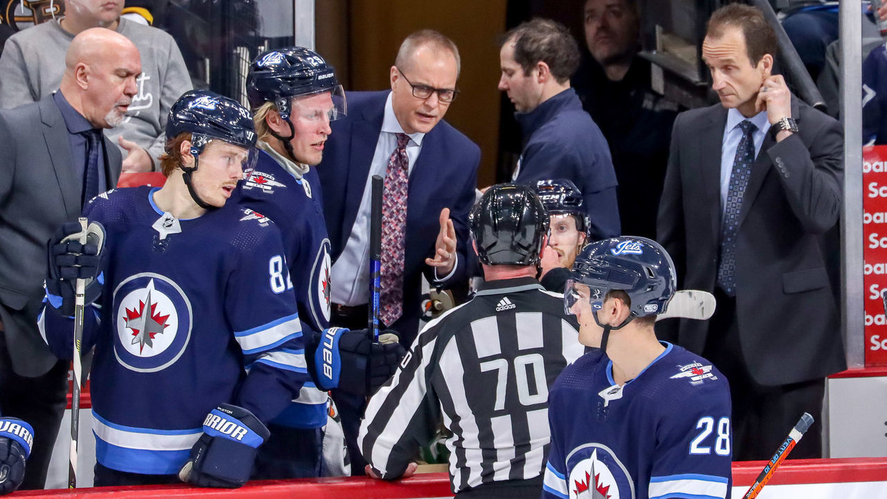 WINNIPEG, MB - JANUARY 31: Head Coach Paul Maurice of the Winnipeg Jets listens to an explanation from linesman Derek Nansen #70 during a second period stoppage in play against the Boston Bruins at the Bell MTS Place on January 31, 2020 in Winnipeg, Manitoba, Canada.
