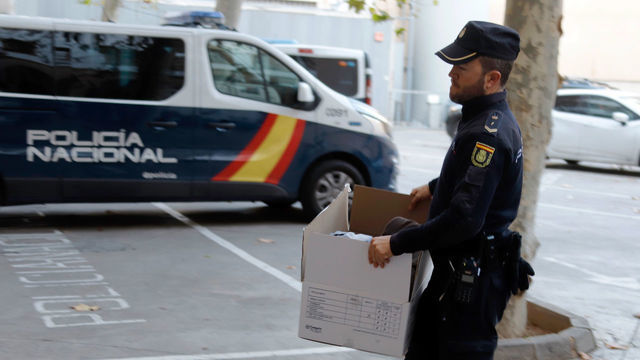 18 January 2020, Spain, Palma: A policeman carries a box with evidence against members of the rocker-like association "United Tribuns". A total of 6 men were arrested. According to the police, the band members had control of the drug trade in several nightclubs and brothels in Mallorca, where their members worked in the security teams. The arrest was a joint operation of the Spanish police, Europol and the German BKA. Photo: Clara Margais/dpa