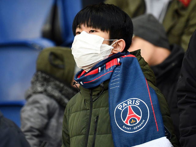 A Paris' supporter wears a protective face mask as a protection against the new coronoavirus, COVID-19 during the French L1 football match between Paris Saint-Germain (PSG) and Dijon, on February 29, 2020 at the Parc des Princes stadium in Paris.