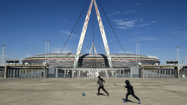 ALLIANZ STADIUM, TURIN, ITALY - 2020/03/04: Two children play with a ball outside desert Allianz Stadium (also known as Juventus Stadium). The Italian Cup semifinal second leg football match between Juventus FC and AC Milan scheduled for Wednesday, March 4 has been postponed indefinitely as part of measures to stop the spread of the coronavirus COVID-19 outbreak in Italy. Media say that Italian government will implement measures to cancel all sporting events for 30 days, although football matches may yet be allowed to take place behind closed doors.