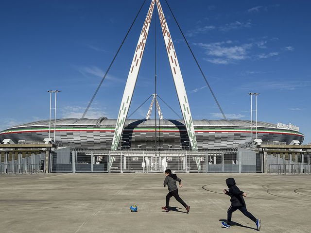 ALLIANZ STADIUM, TURIN, ITALY - 2020/03/04: Two children play with a ball outside desert Allianz Stadium (also known as Juventus Stadium). The Italian Cup semifinal second leg football match between Juventus FC and AC Milan scheduled for Wednesday, March 4 has been postponed indefinitely as part of measures to stop the spread of the coronavirus COVID-19 outbreak in Italy. Media say that Italian government will implement measures to cancel all sporting events for 30 days, although football matches may yet be allowed to take place behind closed doors.