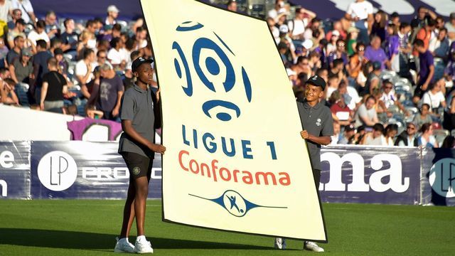 Boys carry a placard bearing the logo of the French first league (Ligue 1) at the start of the French L1 football match Toulouse against Dijon on August 17, 2019 at the Municipal Stadium in Toulouse, southern France.