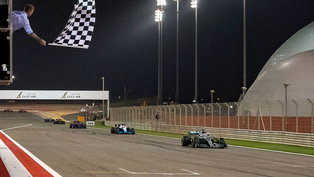Former British football player David Beckham (L) waves the checkered flag as Mercedes' British driver Lewis Hamilton crosses the finish line during the Formula One Bahrain Grand Prix at the Sakhir circuit in the desert south of the Bahraini capital Manama, on March 31, 2019.