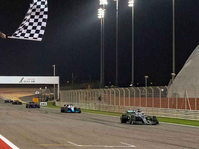 Former British football player David Beckham (L) waves the checkered flag as Mercedes' British driver Lewis Hamilton crosses the finish line during the Formula One Bahrain Grand Prix at the Sakhir circuit in the desert south of the Bahraini capital Manama, on March 31, 2019.