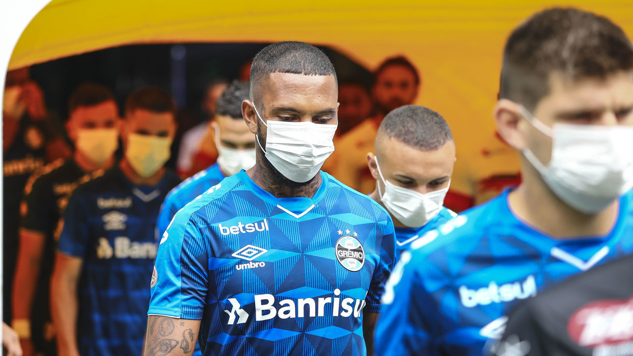 PORTO ALEGRE, BRAZIL - MARCH 15: Players of Gremio enter the field wearing masks before the match between Gremio and Sao Luiz as part of the Rio Grande do Sul State Championship 2020, to be played behind closed doors at Arena do Gremio Stadium, on March 15, 2020 in Porto Alegre, Brazil. The Government of the State of Rio Grande do Sul issued a list of new guidelines to help prevent the spread of the Coronavirus which included games played with closed doors and no public. According to the Ministry of Health, as of Saturday, March 14, Brazil had 121 confirmed cases of coronavirus.