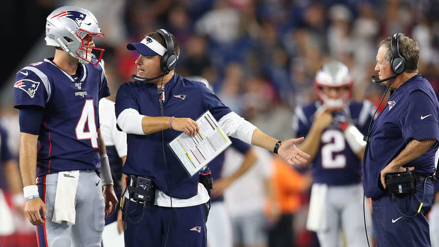FOXBOROUGH, MASSACHUSETTS - AUGUST 22: Jarrett Stidham #4 of the New England Patriots talks with Offensive Coordinator Josh McDaniels and Head Coach Bill Belichick during the preseason game between the Carolina Panthers and the New England Patriots at Gillette Stadium on August 22, 2019 in Foxborough, Massachusetts.