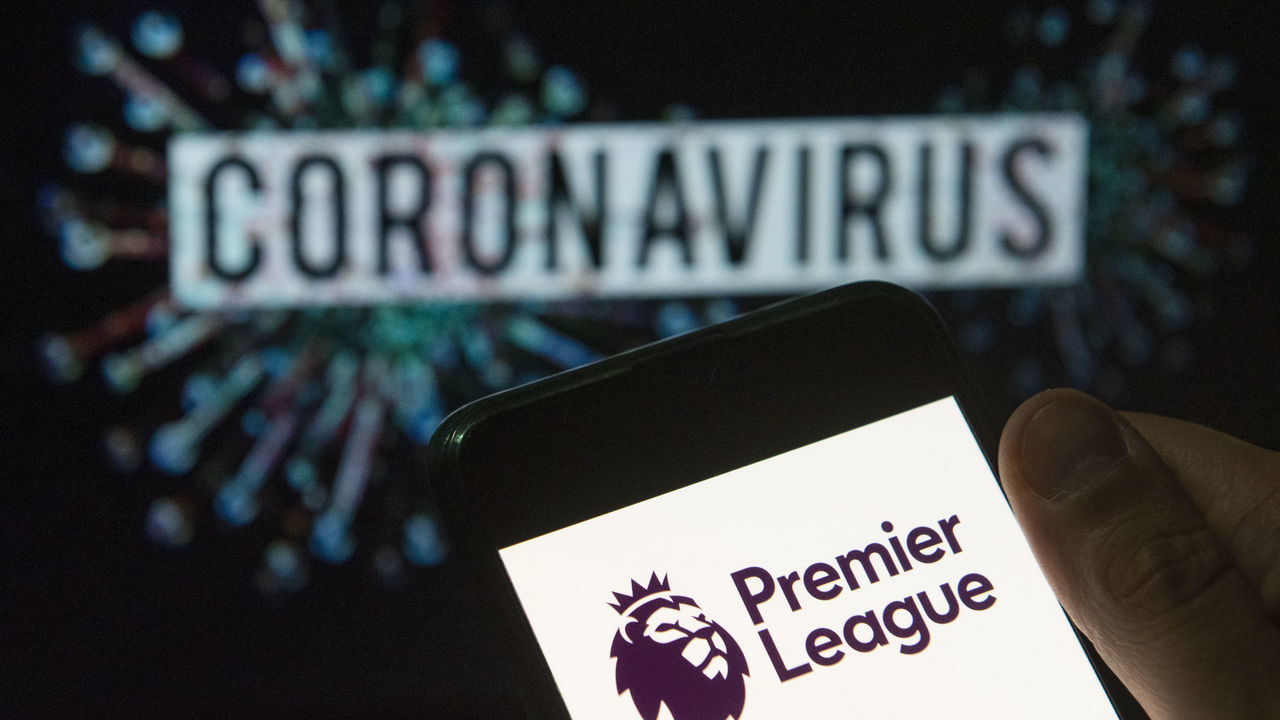 CHINA - 2020/03/24: In this photo illustration the top level of the English football league Premier League logo seen displayed on a smartphone with a computer model of the COVID-19 coronavirus on the background. (Photo Illustration by Budrul Chukrut/SOPA Images/LightRocket via Getty Images)