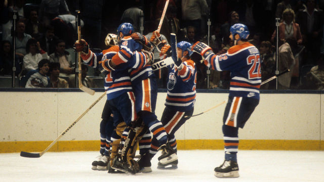 UNIONDALE, NY - MAY 10: Goalie Grant Fuhr #31, Kevin Lowe #4, Wayne Gretzky #99 and Charlie Huddy #22 of the Edmonton Oilers celebrate on the ice after defeating the New York Islanders in Game 1 of the 1984 Stanley Cup Finals on May 10, 1984 at the Nassau Coliseum in Uniondale, New York.