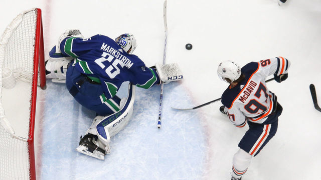 VANCOUVER, BC - DECEMBER 23: Vancouver Canucks Goalie Jacob Markstrom (25) makes a save while watched by Edmonton Oilers Center Connor McDavid (97) during their NHL game at Rogers Arena on December 23, 2019 in Vancouver, British Columbia, Canada.